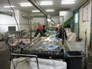 Workers sort an incoming stream of various plastics, mixed with some pieces of un-recyclable litter